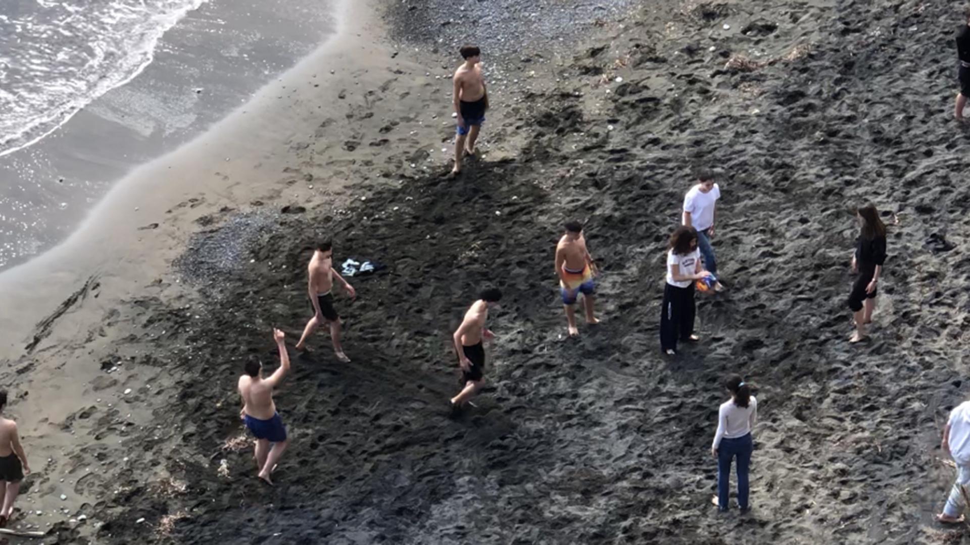 dettaglio di spiaggia di sabbia scura con persone viste dall'alto